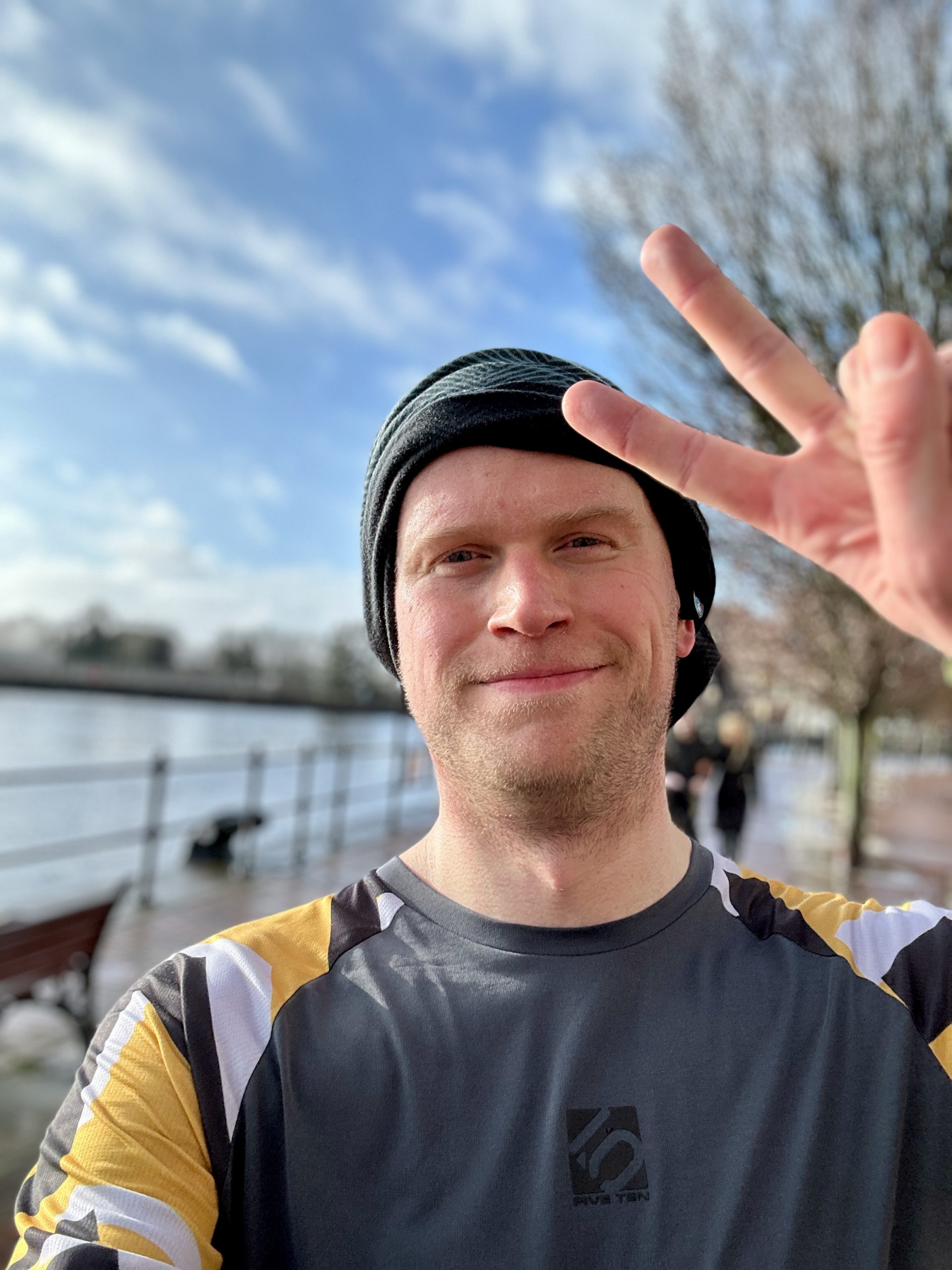A man wearing a marathon long sleeve t-shirt flashing a peace sign.